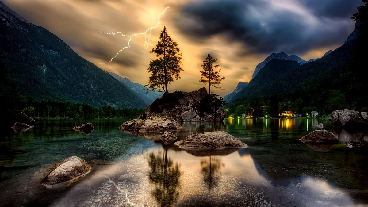 山の湖の上の夕焼けと稲妻の写真