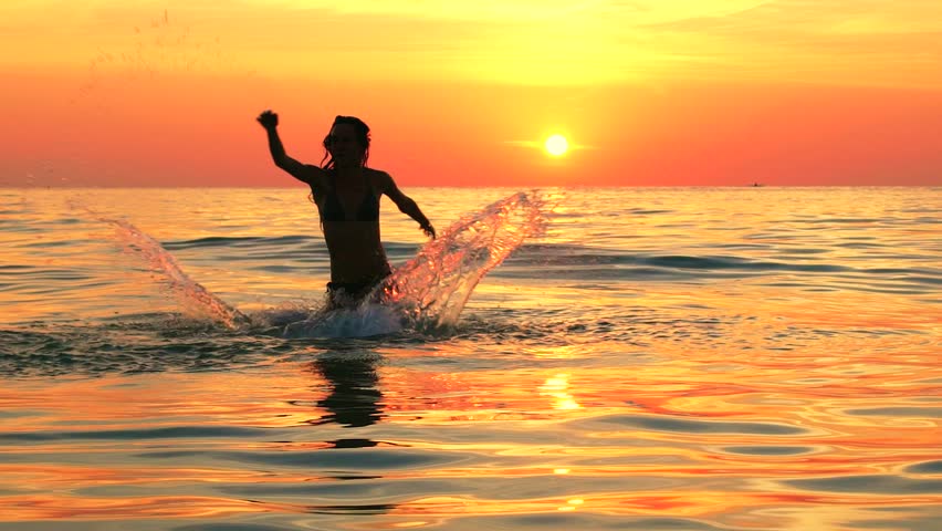 Foto dunha nena no mar ao pór do sol