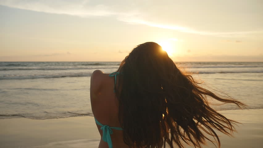Foto av en jente på sjøen ved solnedgang
