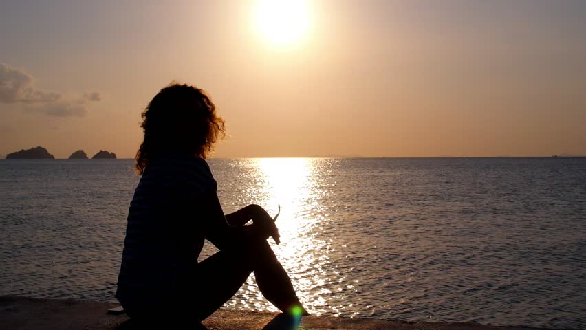 Foto av en jente på sjøen ved solnedgang