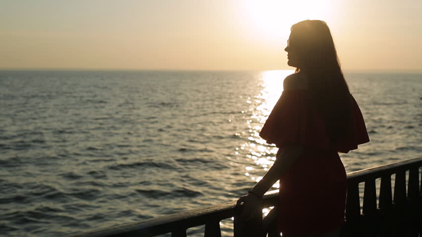 Foto no meitenes uz jūras saulrieta laikā
