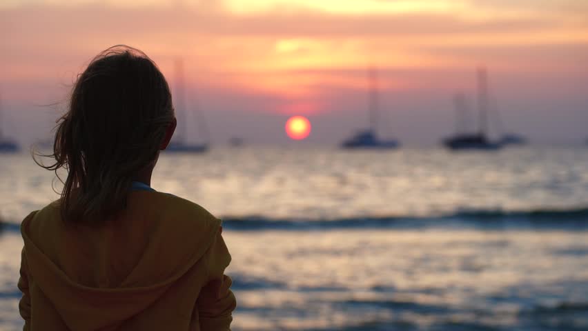 Gambar seorang gadis di laut ketika matahari terbenam