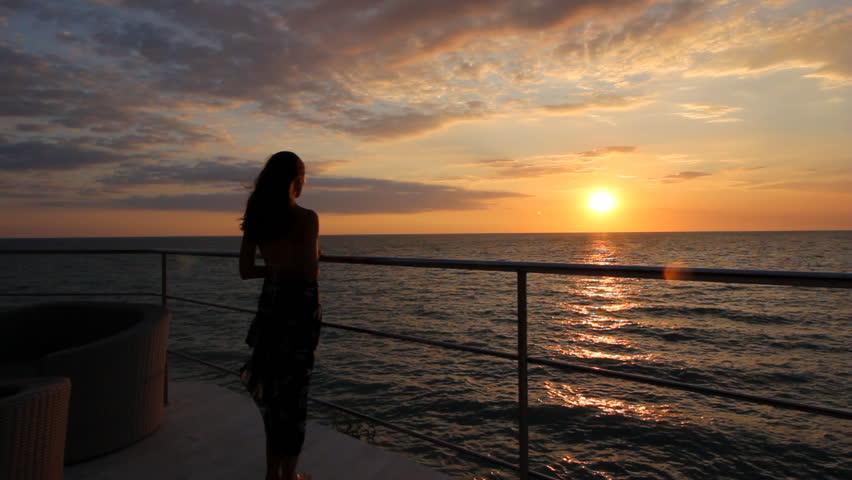 Foto e një vajze në det në perëndim të diellit