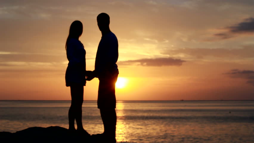 Foto de um casal no mar ao pôr do sol