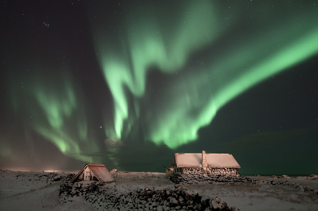 Aurora Boreal sobre casas na Islândia