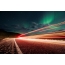 Lange belichtingsfoto: noorderlicht en strepen van licht op de wegen van Alaska